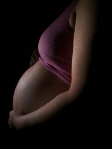 donna incinta vista di profilo su sfondo nero